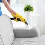 Woman,cleaning,couch,with,vacuum,cleaner,at,home